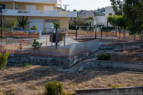 a fence in front of a building with trees at Unbeatable View, Family apartment in Rafina