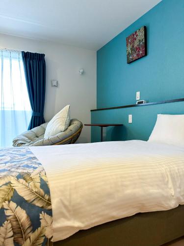 a bedroom with a large bed and a chair at KOHALA　HOTEL in Naha
