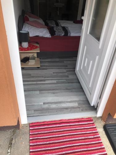 a door leading into a bedroom with a bed and a rug at Grevia Apartmanok in Poroszló