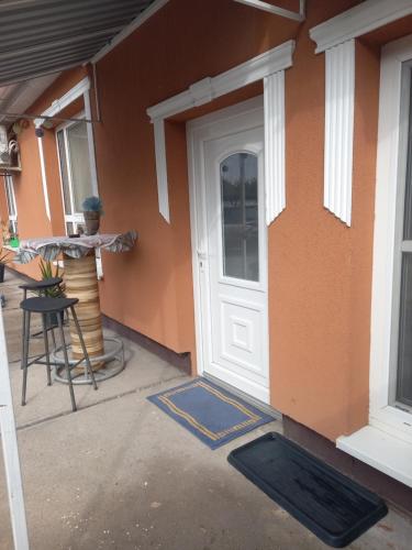 a front door of a house with a table at Grevia Apartmanok in Poroszló