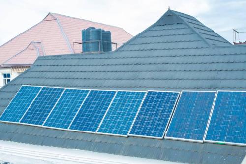 a roof with blue solar panels on it at Kays Apartment in Okpanam