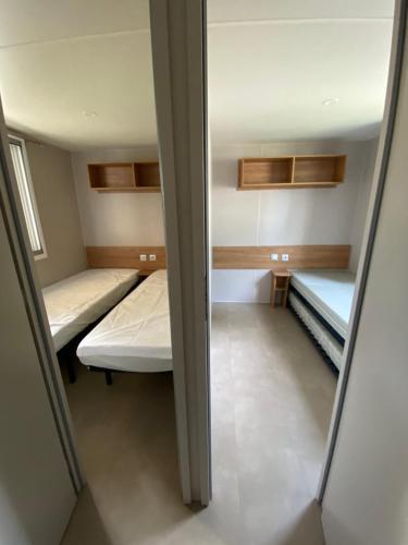 une petite chambre avec deux lits et un miroir dans l'établissement Mobil Home - Camping Les Oyats 4 étoiles, à Seignosse