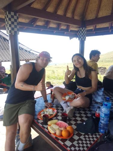 a man and woman sitting on a picnic table with food at Poetri Bungalow & Restaurant in Senaru