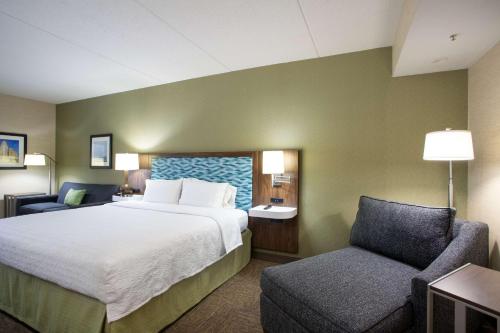 a hotel room with a bed and a chair at Hampton Inn Buffalo-South/I-90 in West Seneca