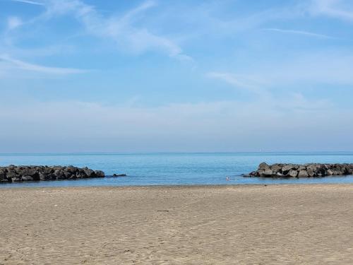 a beach with rocks in the water and a blue sky at Leonardo Da Vinci Guest House in Fiumicino