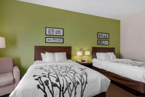 two beds in a hotel room with green walls at Sleep Inn & Suites Cave City in Cave City