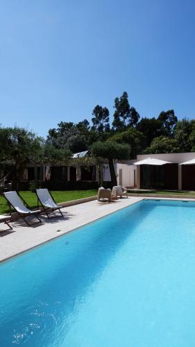 a large blue swimming pool with two lounge chairs at Eido do Luou - Casa de férias com piscina in Santa Cruz do Lima