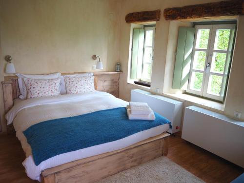 a bedroom with a bed with a blue blanket and two windows at Papaevangelou Hotel in Papigko