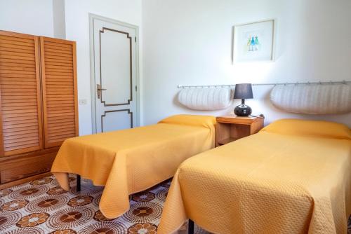 deux lits dans une chambre avec des draps jaunes dans l'établissement S303 - Sirolo, ampio trilocale in zona tranquilla, à Sirolo