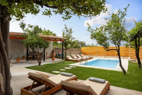 a backyard with a swimming pool and a yard with lounge chairs at The Olive Mill House - Luxe Villa, Classic Charm in Prinés