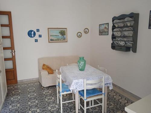 a table with chairs and a vase on top of it at Casa Danero "U dedotu" - Centro storico di Carloforte in Carloforte