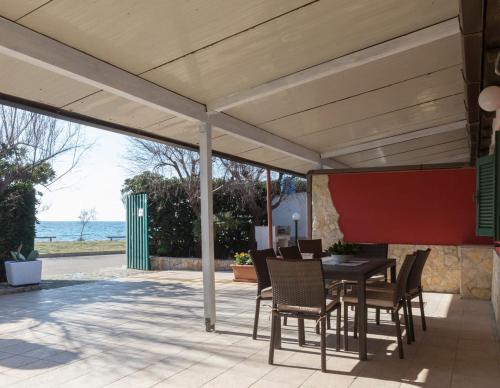 a patio with a table and chairs and the ocean at Villetta Lana 1 fronte mare a Punta Grossa di Punta Prosciutto in Punta Prosciutto