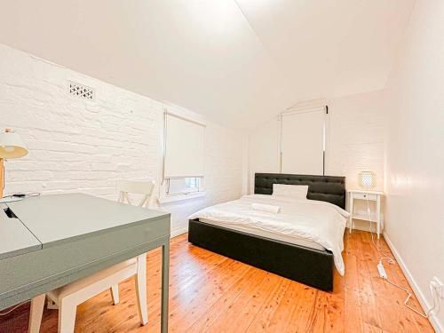 シドニーにあるUltimo Homestayのベッドと机が置かれた寝室