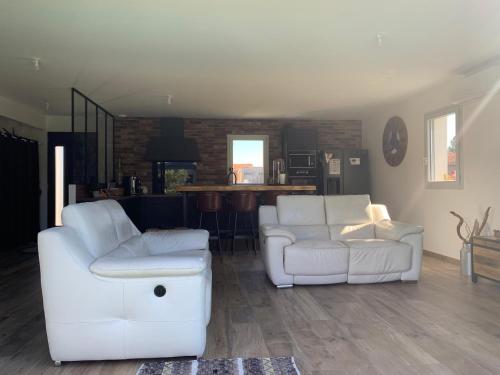 un salon avec deux canapés blancs et une cuisine dans l'établissement Maison au calme avec piscine chauffée à 10 mn des plages, à Seignosse