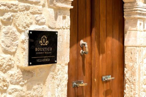 a wooden door with a sign on the side of a building at Roustico Luxury Villa Heated Whirpool in Rethymno Town