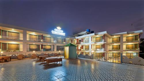 a hotel with tables and chairs in front of it at Grand Continent Morjim in Morjim