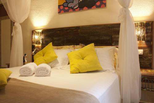 a bedroom with a white bed with yellow pillows at Pousada de Charme Emirados in Ilhabela