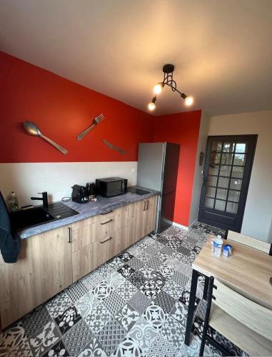 Il comprend une cuisine dotée de murs rouges, d'un réfrigérateur et d'une table. dans l'établissement Limoges à la Plage proche de tout avec parking, à Limoges