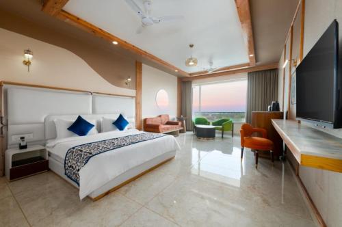 a hotel room with a bed and a flat screen tv at Grand Continent Morjim in Morjim