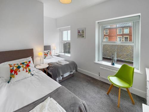 a bedroom with a bed and a chair and a window at Beachside Cottage Minehead in Minehead