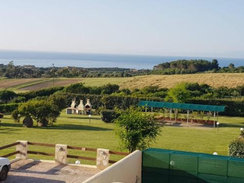 Elle offre une vue sur un parc avec une clôture et l'océan. dans l'établissement La Muddizza appartement avec piscine, à Valledoria