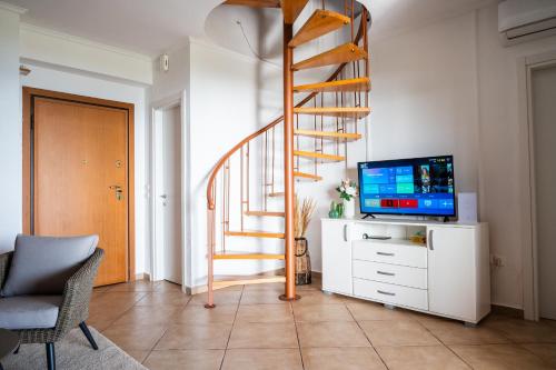 a living room with a staircase and a television at Villa Jana - the Great Escape in Nea Skioni