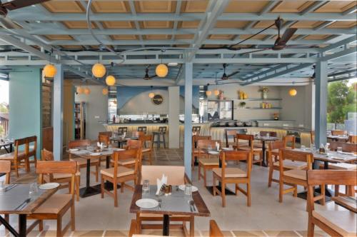a dining room with wooden tables and chairs at Grand Continent Morjim in Morjim