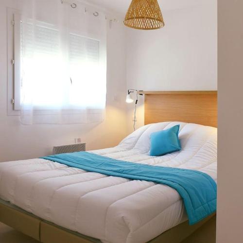 - un grand lit blanc avec un oreiller bleu dans l'établissement Appt T4 Accès Plage, piscine privée, clim N3-4, à Linguizzetta