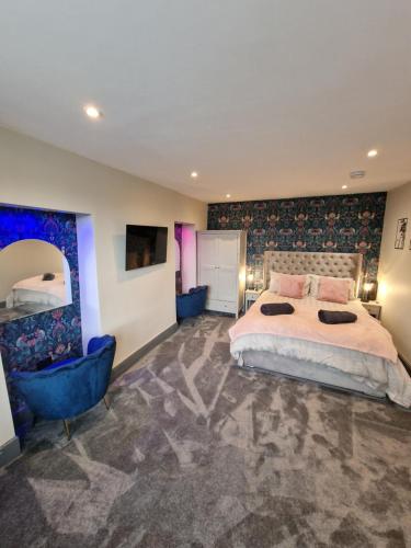 Un dormitorio con una cama grande y una silla azul. en Townhouse - 6 Bed Hot Tub House, en Bowness-on-Windermere