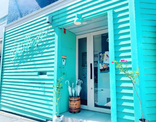 a blue building with an open door with umbrellas at HOSTEL CHILLAX in Osaka