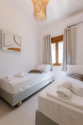 two beds in a room with white walls and a chandelier at Naxian Harmony Town Suites in Naxos Chora