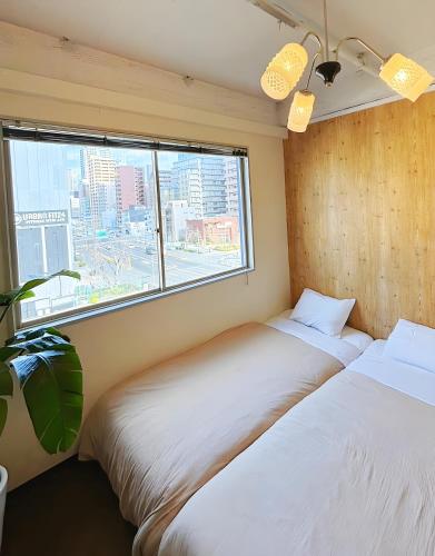 two beds in a room with a window at HOSTEL CHILLAX in Osaka