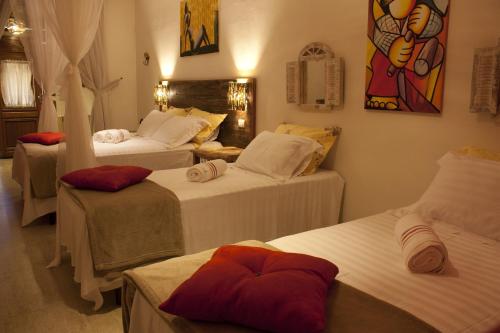 a room with three beds and a painting on the wall at Pousada de Charme Emirados in Ilhabela