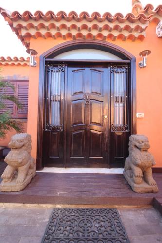 a large wooden door of a house with two stone statues at Villa Jardín de Buda in Arona
