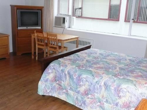 a bedroom with a bed and a table and a television at English Bay Hotel in Vancouver