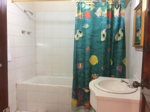 a bathroom with a shower curtain with a tub and a sink at Hostal el castillo ingapirca in Ingapirca