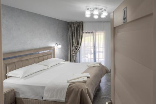 a bedroom with a bed with white sheets and a window at Casa Patry in Călimăneşti