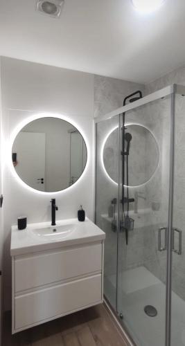 a bathroom with a sink and a shower with a mirror at Burela Mariña Playa in Burela de Cabo