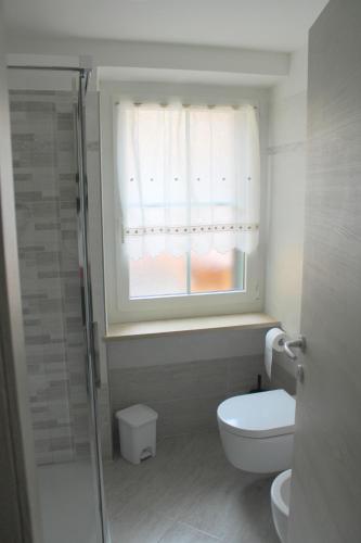 a bathroom with a toilet and a window at Hotel Villa Cima Undici in Pozza di Fassa