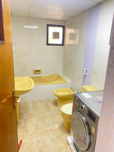 a bathroom with a toilet and a sink and a washing machine at Tourist Club For men only in Abu Dhabi