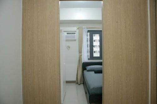 a door to a room with a bed and a mirror at Quiet Oasis in Bloom Residences in Manila