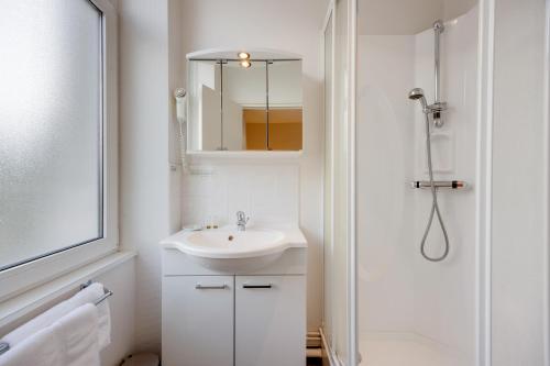 a white bathroom with a sink and a shower at Brit Hotel Confort Bagnoles Normandie in Bagnoles de l'Orne