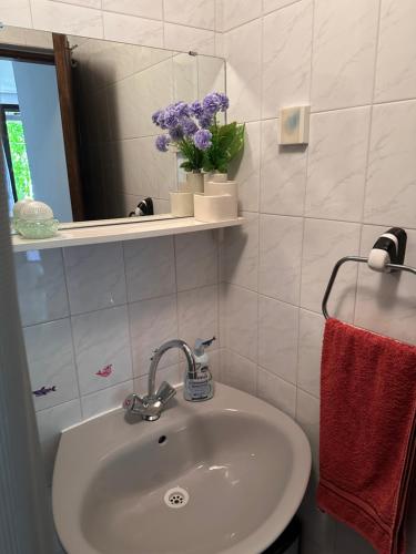 a bathroom with a sink and a mirror and purple flowers at Jasna in Poreč