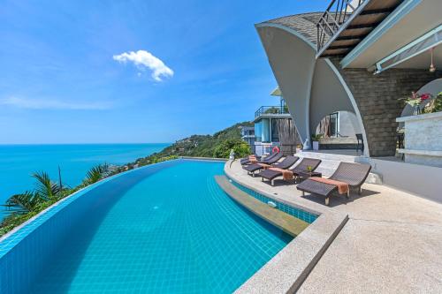 an infinity pool with chairs and the ocean in the background at Scenery Samui in Chaweng
