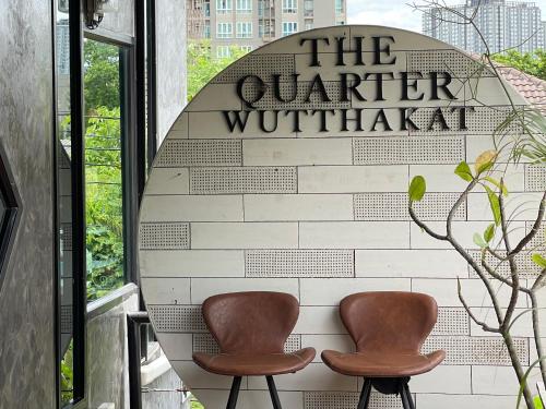 two brown chairs sitting in front of a sign at The Quarter Wutthakat in Bang Khun Thian