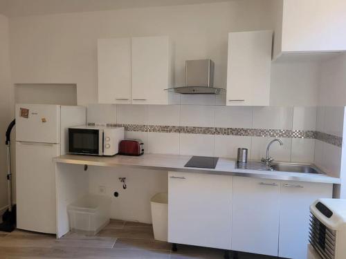 une cuisine avec des armoires blanches, un évier et un micro-ondes dans l'établissement Agde centre historique location de samedi à samedi, à Agde