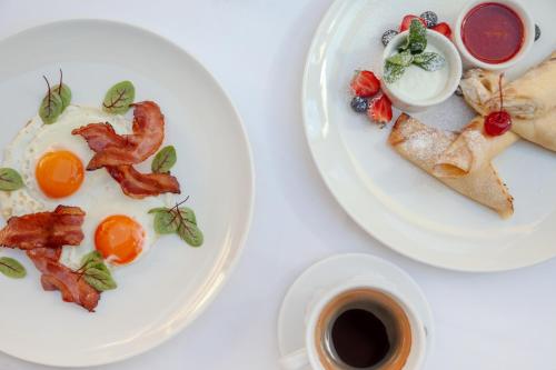 two plates of breakfast food on a table with a cup of coffee at Pušynė in Birštonas
