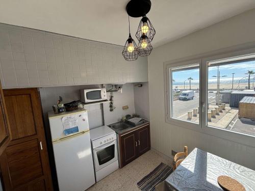 Elle comprend une petite cuisine avec un réfrigérateur blanc et une fenêtre. dans l'établissement Appt 3 pièces 6 personnes avec parking, à 300m des commerces - FR-1-229C-49, à Port-la-Nouvelle