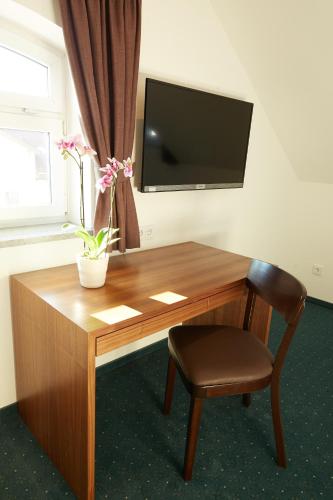 a wooden desk with a chair and a flat screen tv at Pfaffinger Hof in Pfaffing