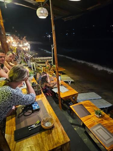 Villa Surf Beach في غالي: مجموعة من الناس يجلسون على طاولات على الشاطئ